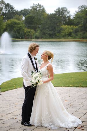 A romantic moment captured by a lake with a fountain and stone patio on a beautiful summer day. little river farms wedding photos