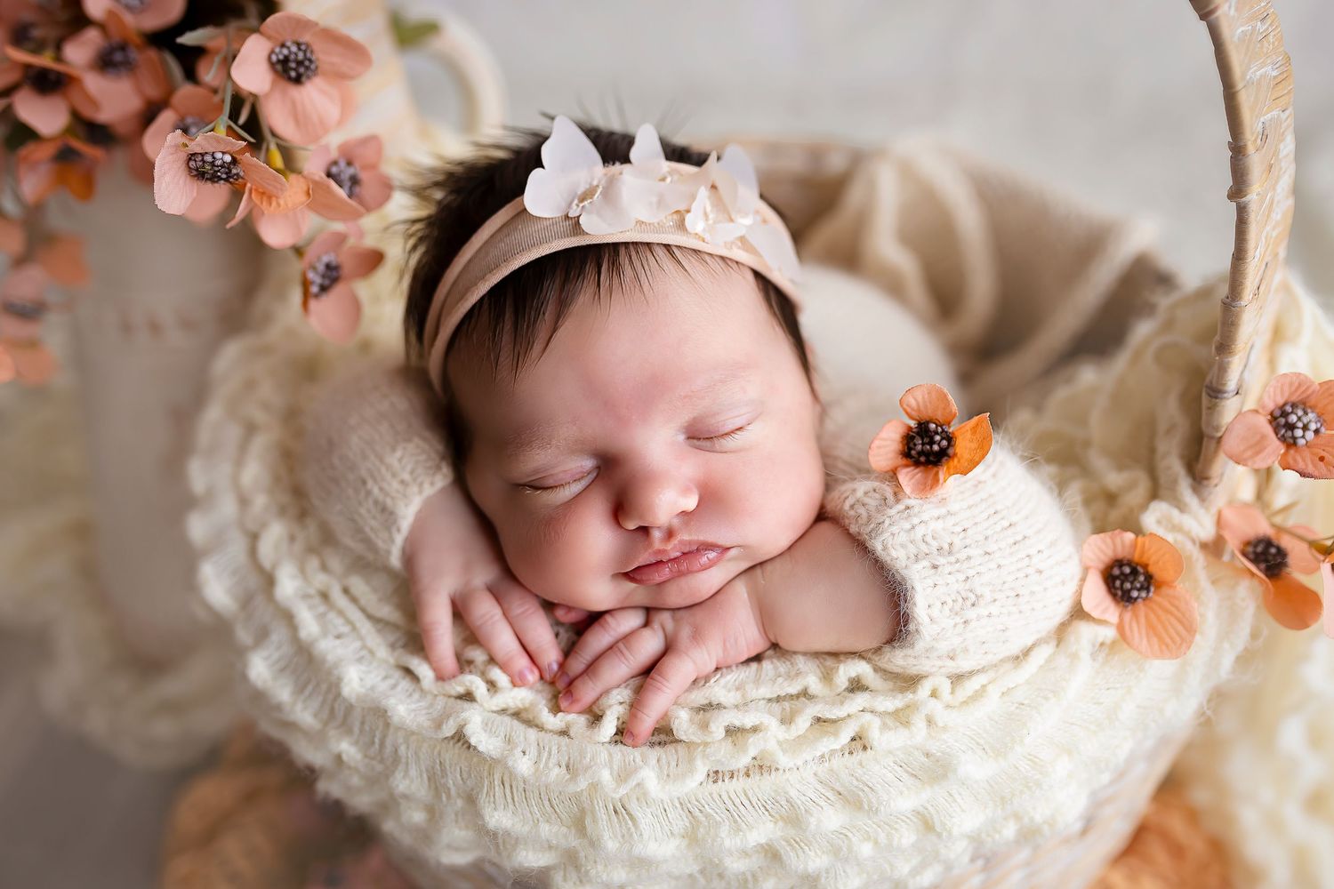 bebe duermiendo dentro de una canasta rodeada de flores usando banda de cabeza con mariposas