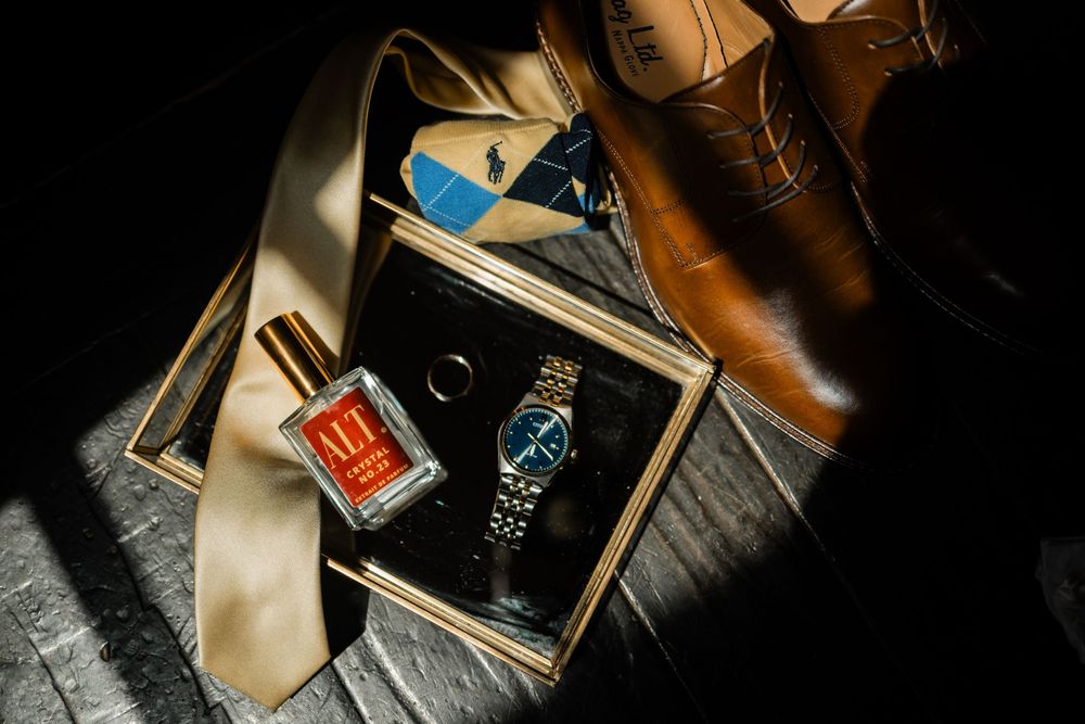 Vintage leather shoes and accessories arranged artistically with a watch and wallet on dark background.