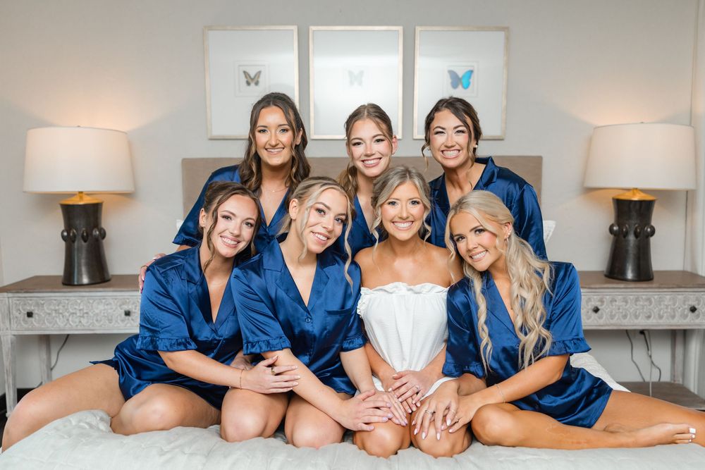 Group wearing matching navy blue robes lounging together during wedding preparations.