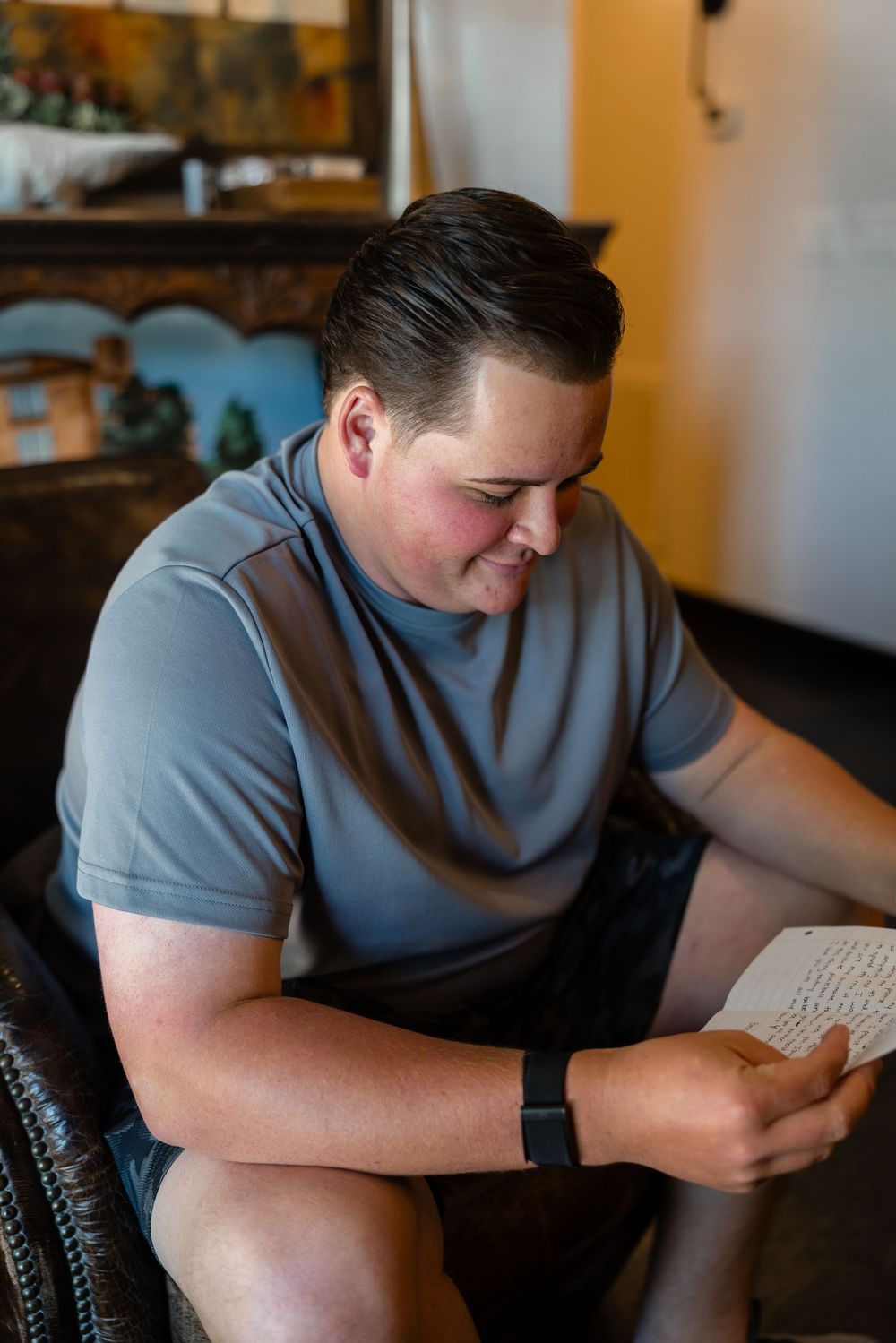 Person in gray t-shirt reading or writing in a casual indoor setting.