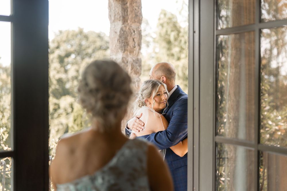 Elderly residents in a nursing home look out large windows at a sunny outdoor view.