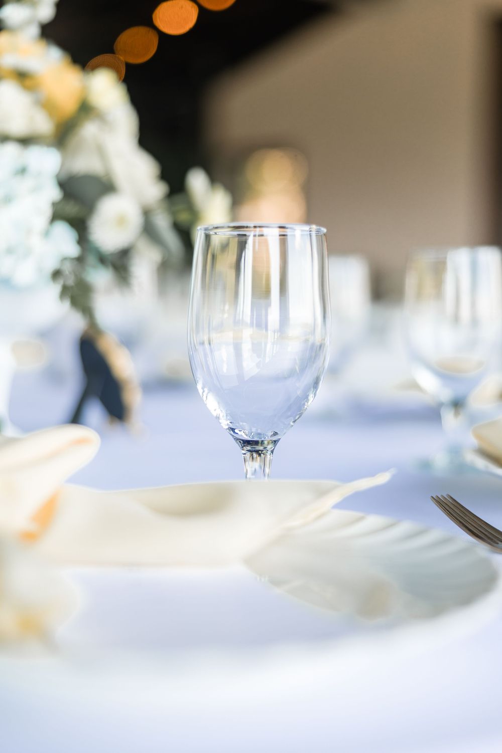Elegant table setting with wine glasses and white linens in soft focus.