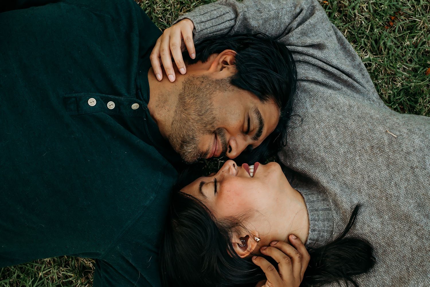 Intimate overhead shot of couple lying in grass sharing a tender moment together.