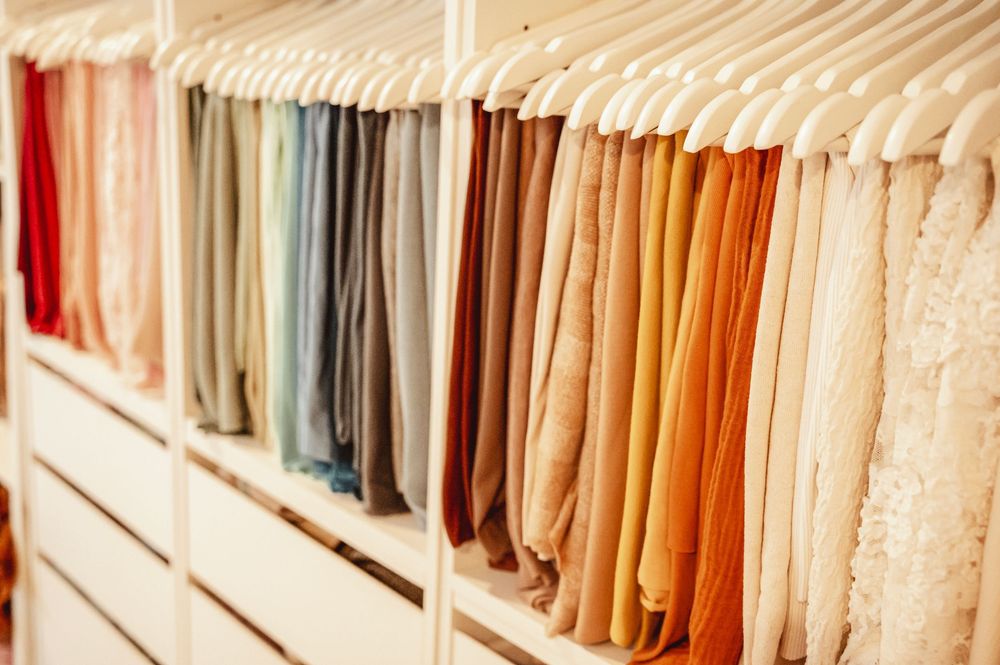 Rows of colorful hanging clothes on retail display racks in a clothing store interior.