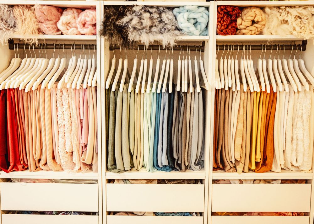 Rows of colorful clothing neatly organized on hangers in a retail closet or wardrobe display.