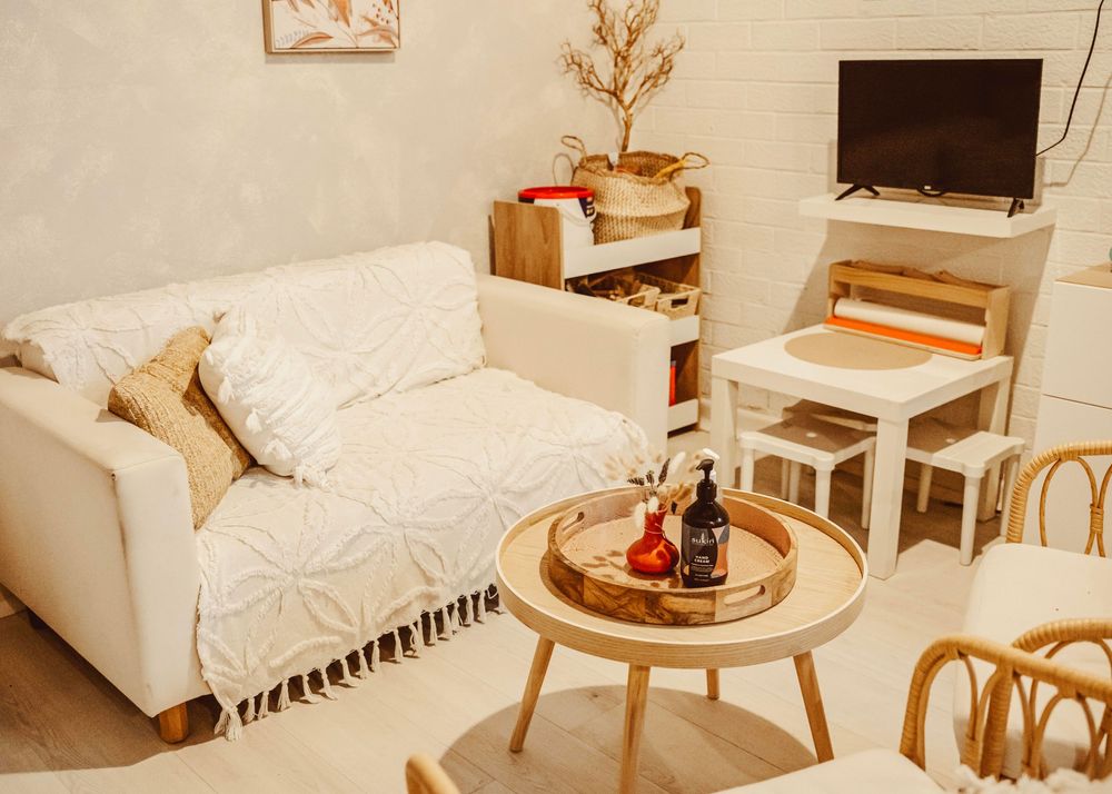 Cozy living room with white sofa, round coffee table, and minimalist decor in warm neutral tones.
