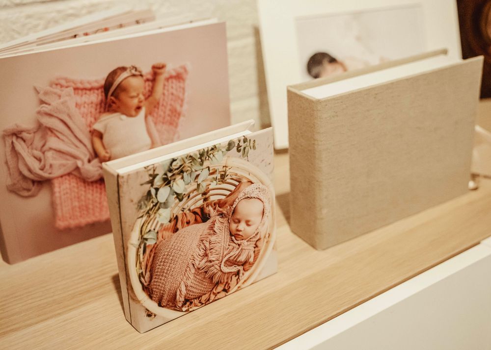 White wall-mounted shelves display an artful arrangement of soft pink and neutral toned photographs and decor items.