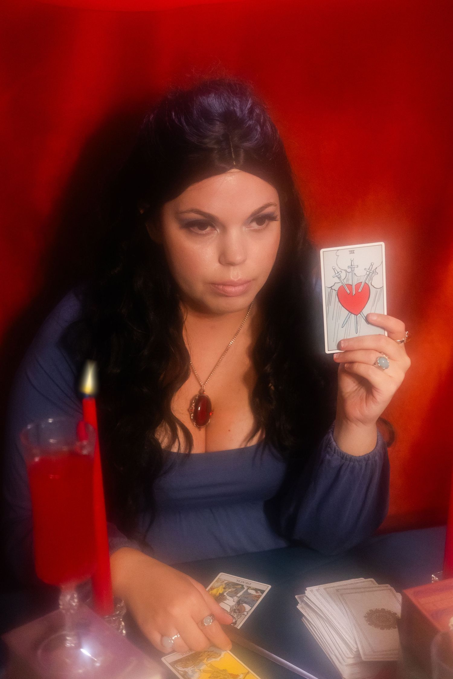 A woman in a navy top holds up playing cards against a red background in a sequence of photos.