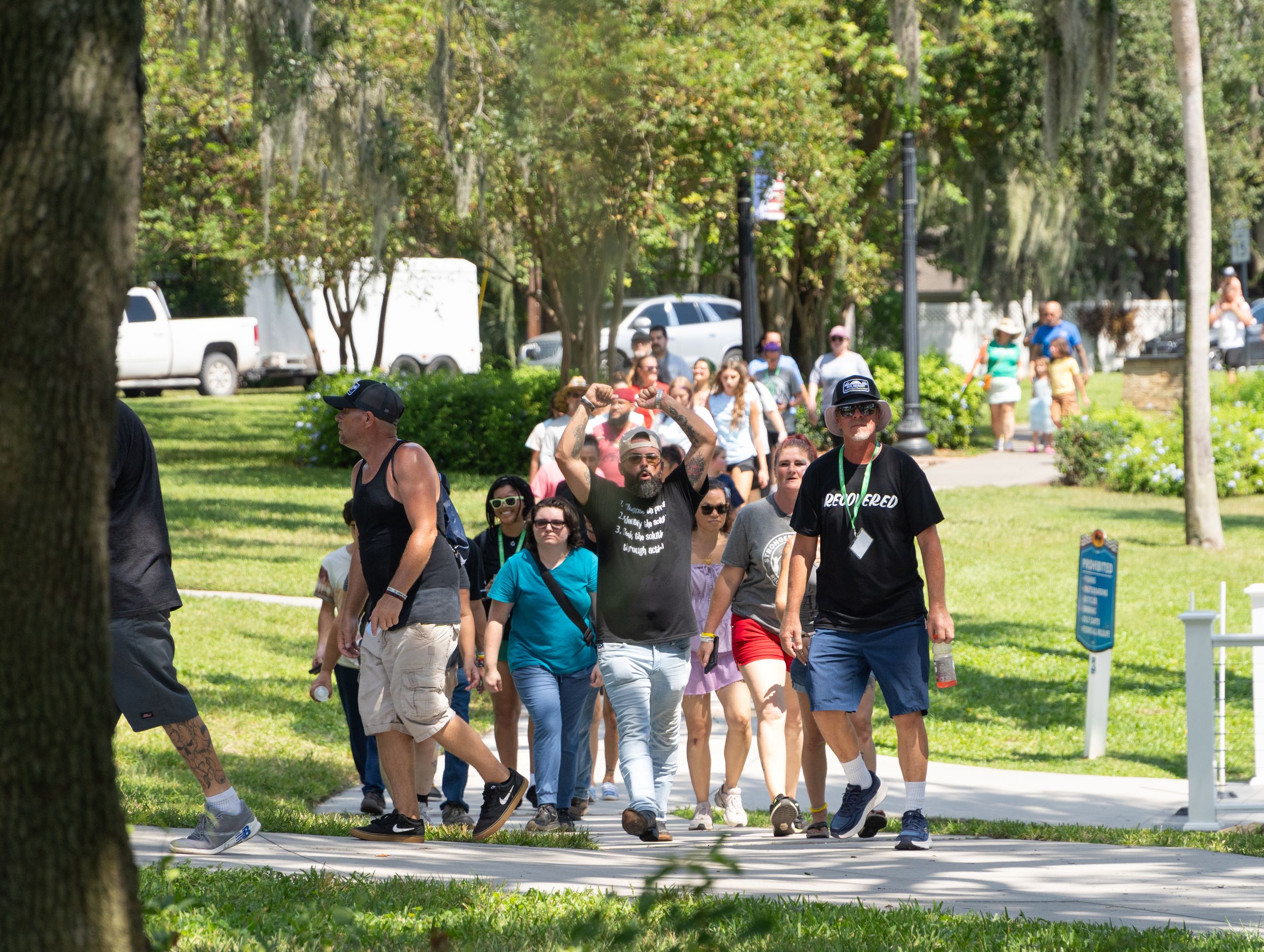 Students walking together on a tree-lined campus pathway during a sunny day at a university.