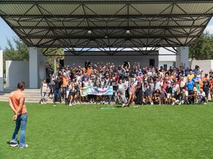 Large crowd of students gathered on a grassy field for an outdoor school assembly event.