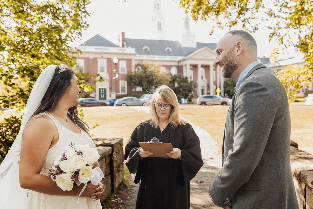 Wedding party shares joyful moments outdoors during fall season with golden leaves in background.