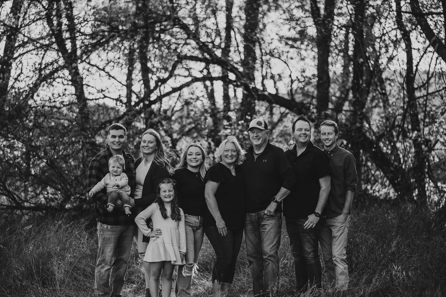 A black and white photo collage shows a group of people posing outdoors in a natural setting.