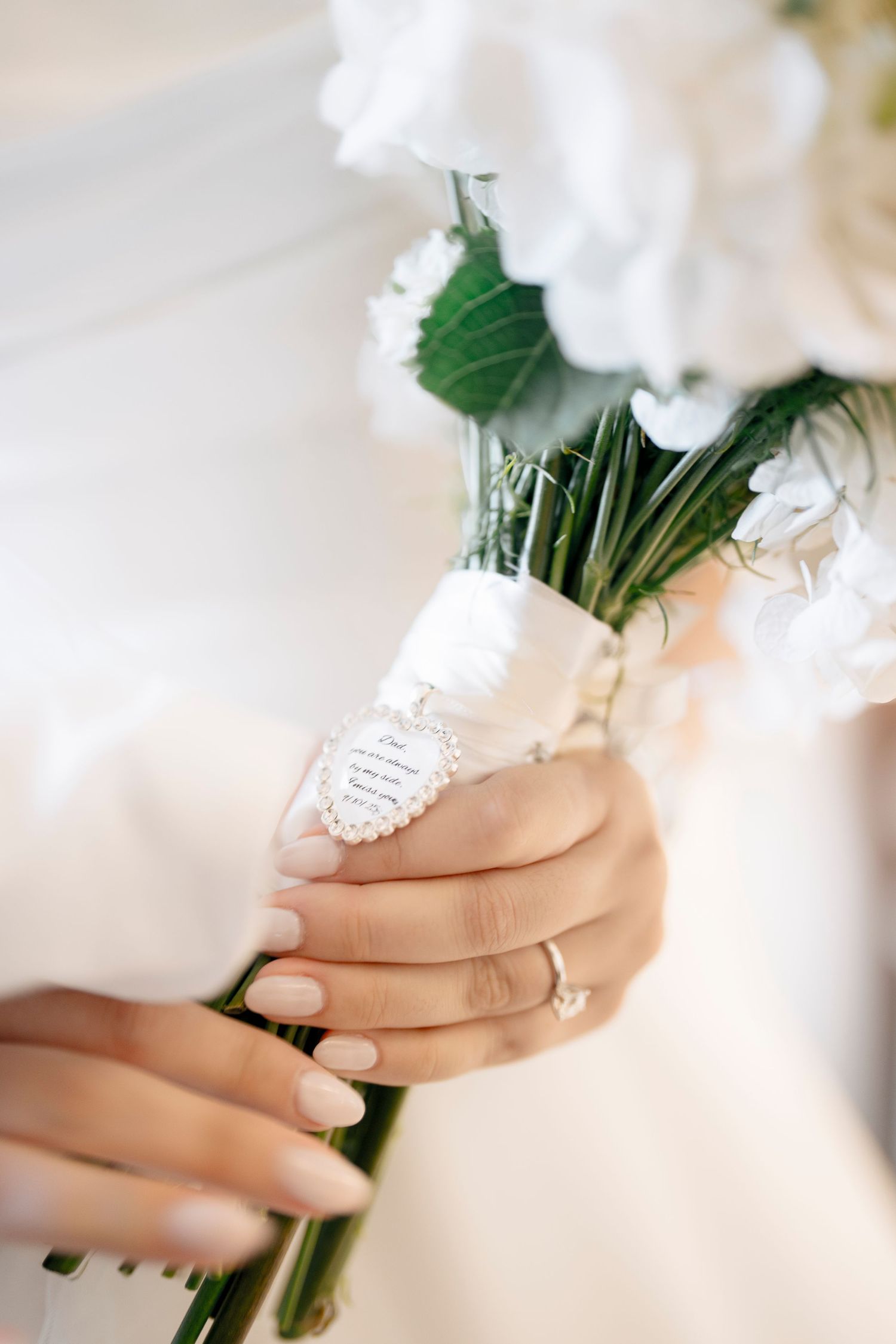 Close-up of hands holding a white wedding bouquet wrapped in delicate lace.