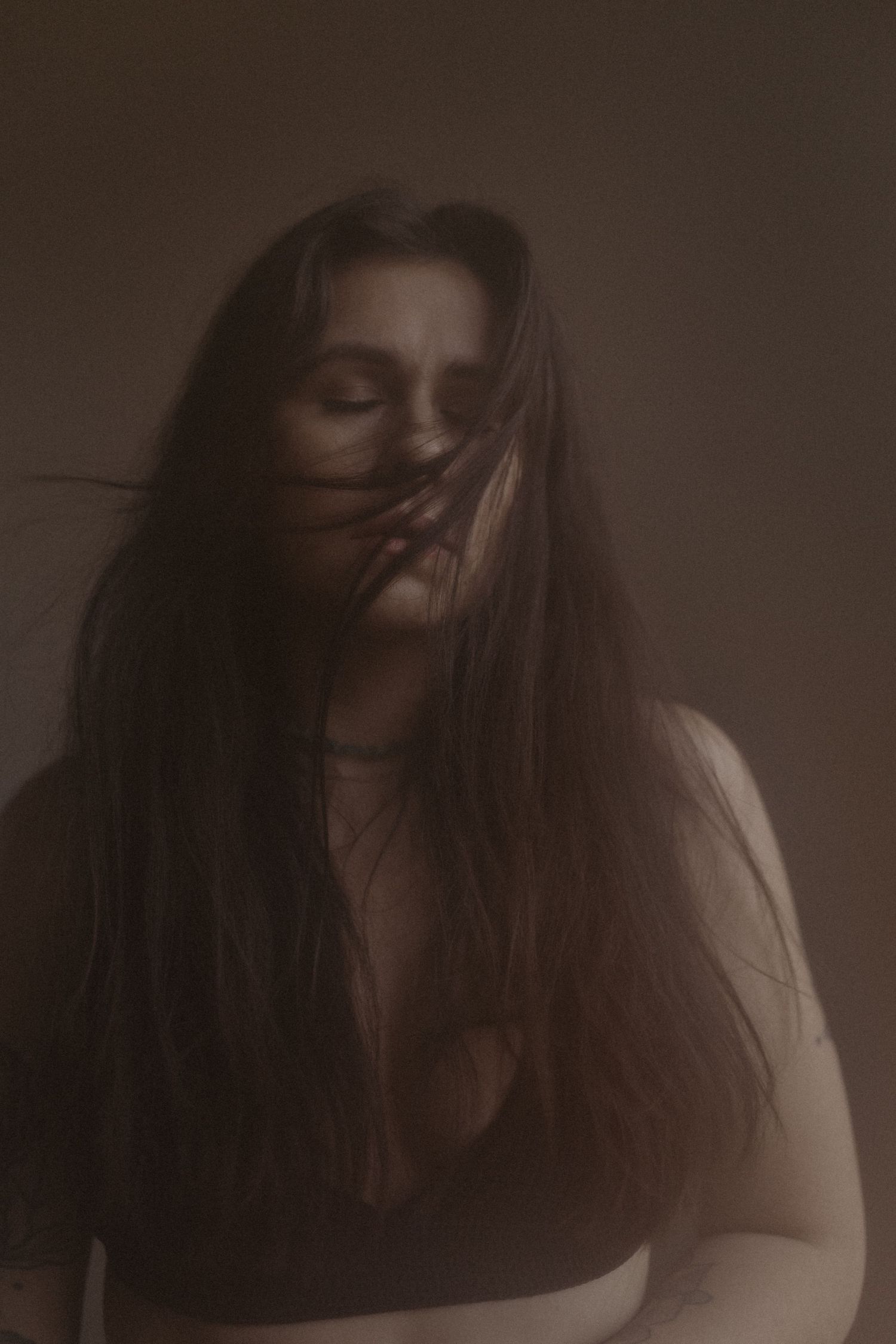A series of moody portraits showing a person with long dark hair against a shadowy background in various poses.