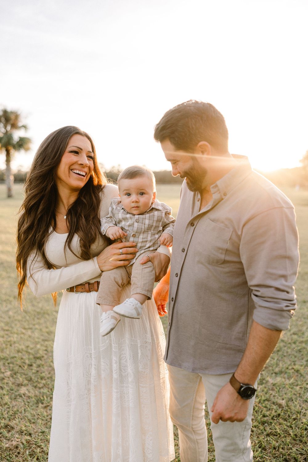 Family shares tender moments together in a sun-drenched field during golden hour photo session.