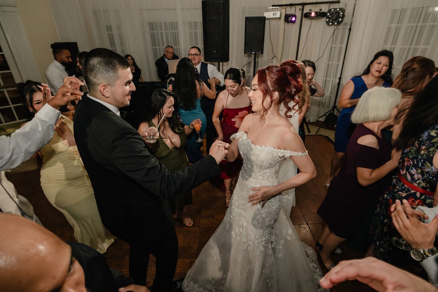 Wedding guests dance and celebrate together on a dimly lit dance floor during a Sacramento evening reception.