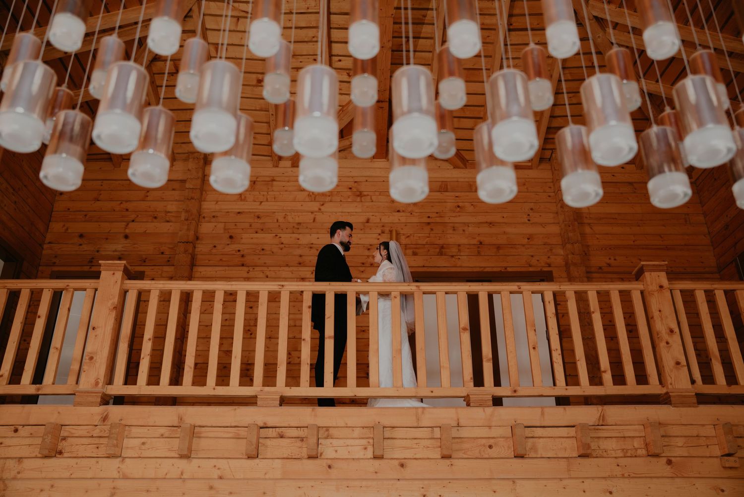 String lights illuminate a rustic wooden barn interior during an evening celebration.