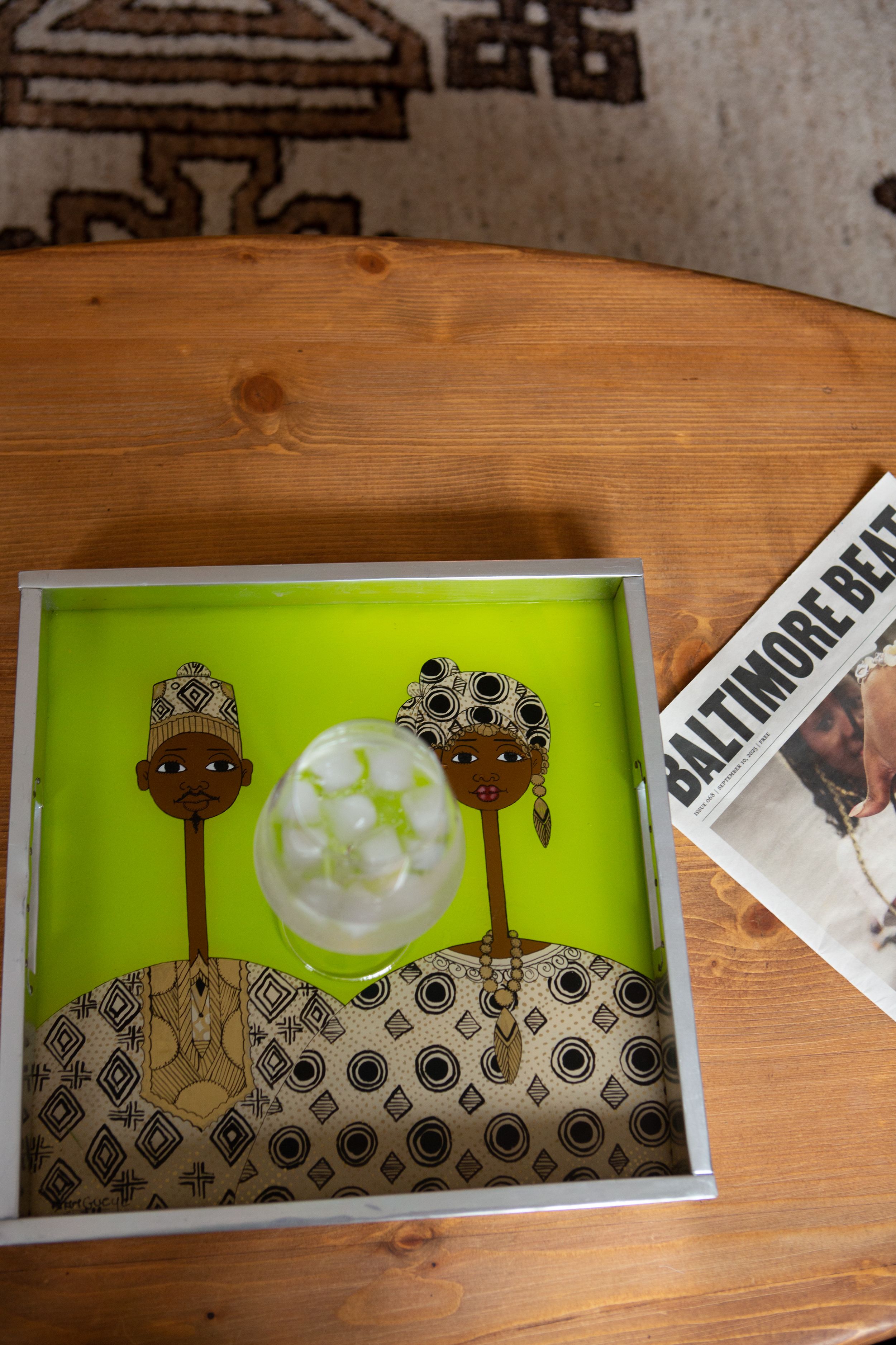 Artistic display showing silhouettes of giraffes against a bright lime green background with a moon in a wooden frame.