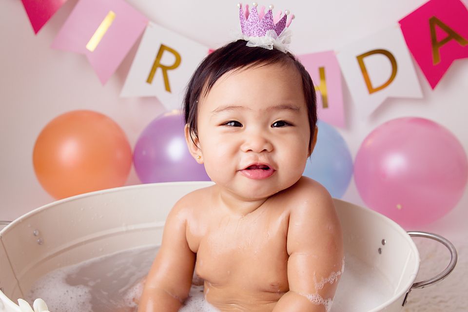 First birthday celebration setup with pink crown, banners and colorful balloons.