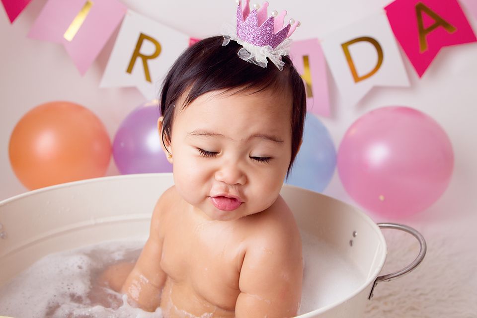 Festive birthday setup with pink banners, colorful balloons, and floral decorations for a baby photoshoot.