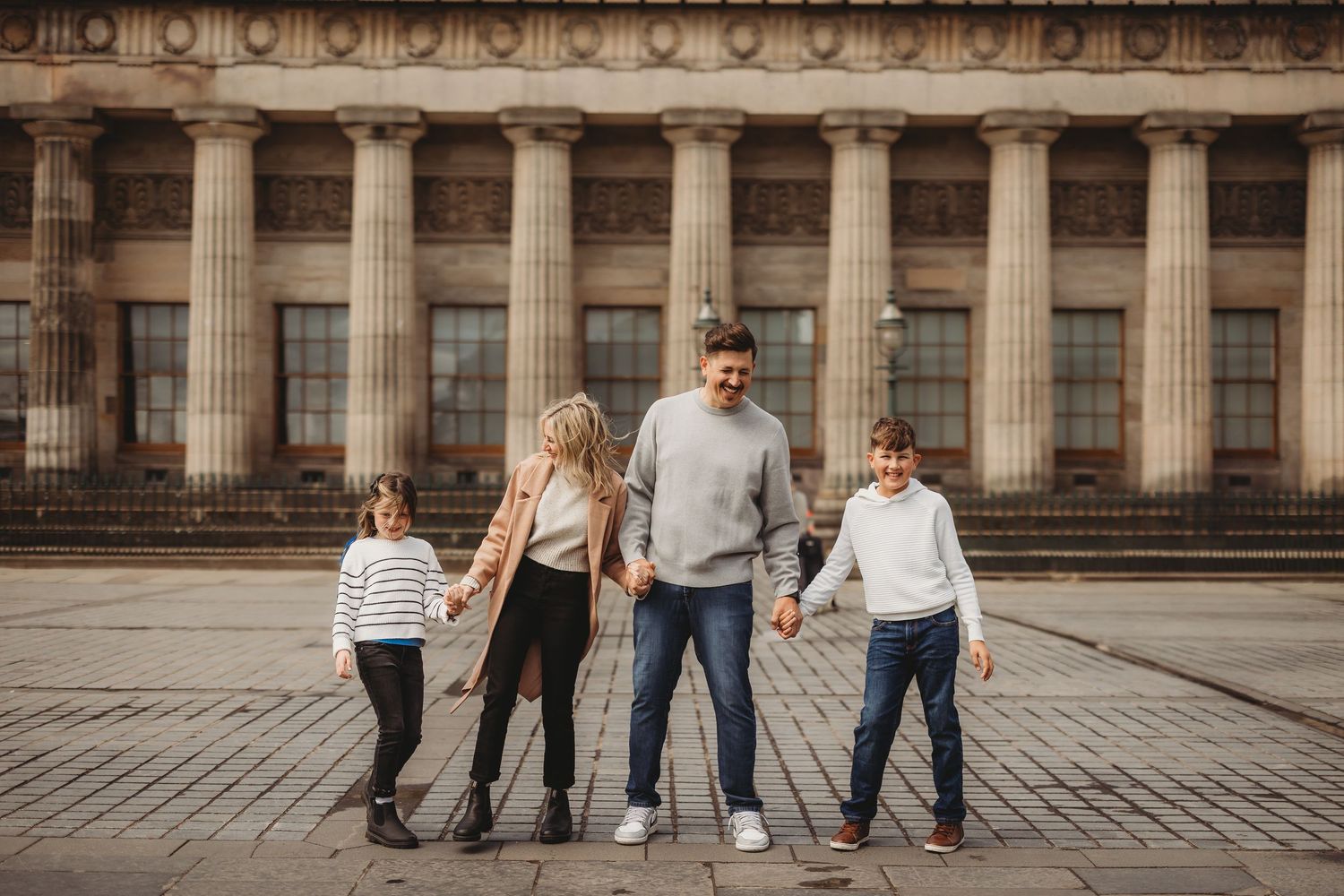 A group of people walking together in front of a historic building with columns and classical architecture.