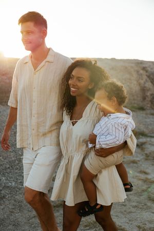 A family enjoys a sunset walk together in light summer clothing against a desert landscape backdrop.