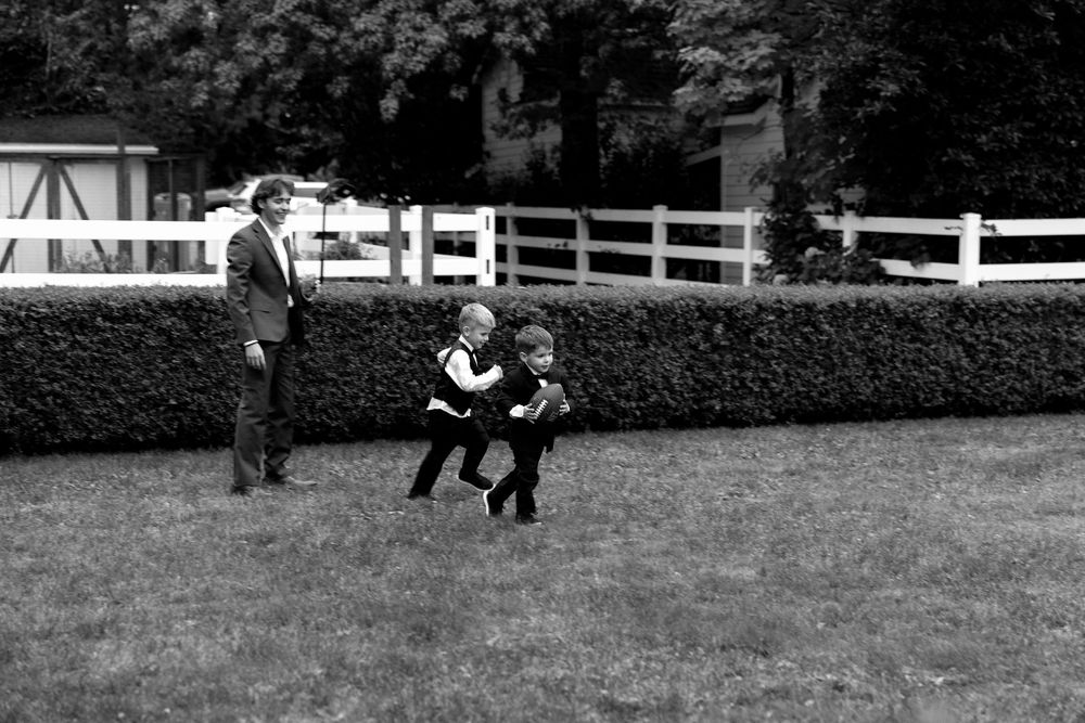 People enjoying outdoor activities on a grassy field with white fencing in the background.