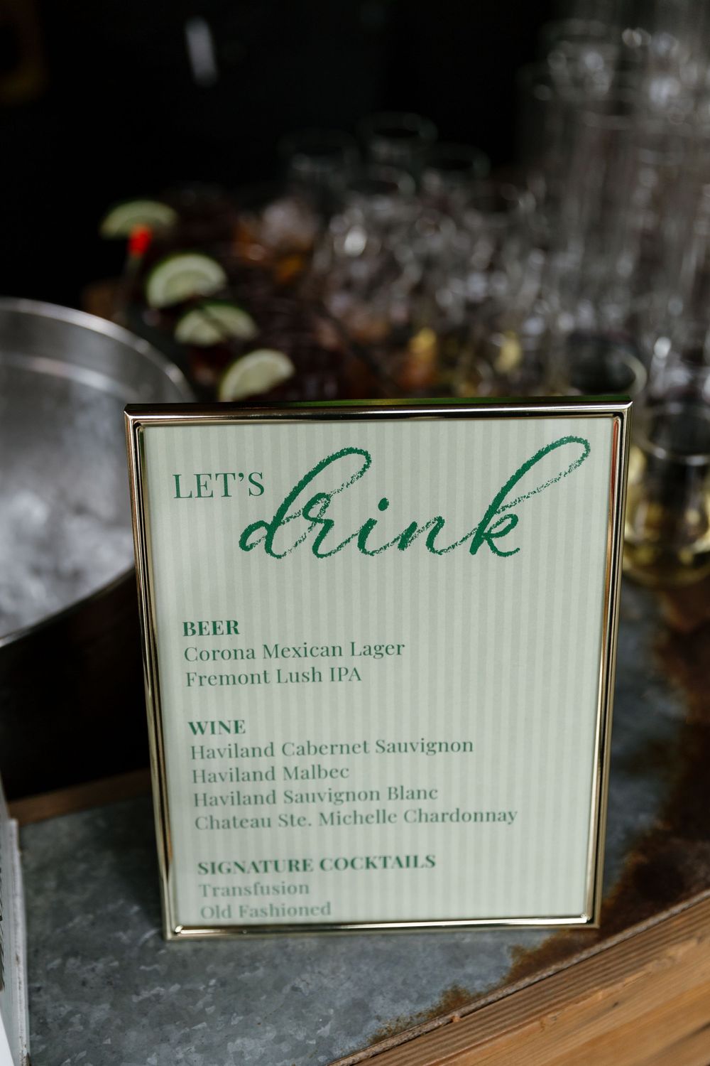 Close-up view of green and gold drink menu cards displaying cocktail and wine selections at a bar.