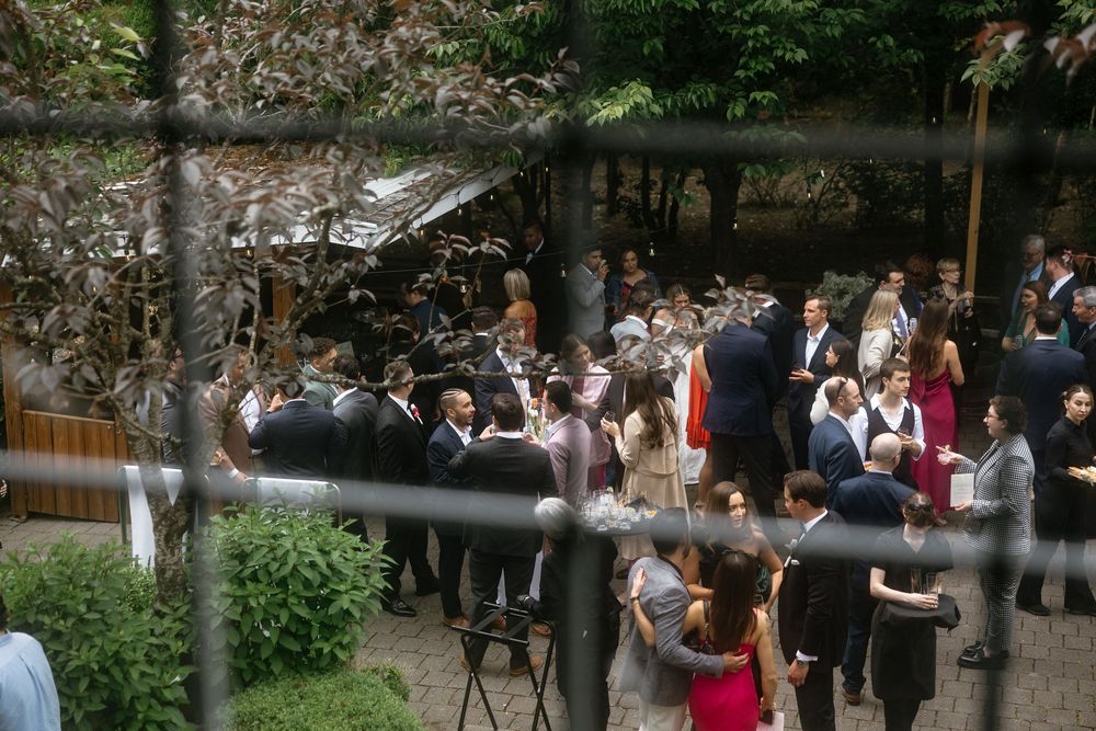 Outdoor wedding reception venue with guests mingling under string lights and rustic wooden decor.