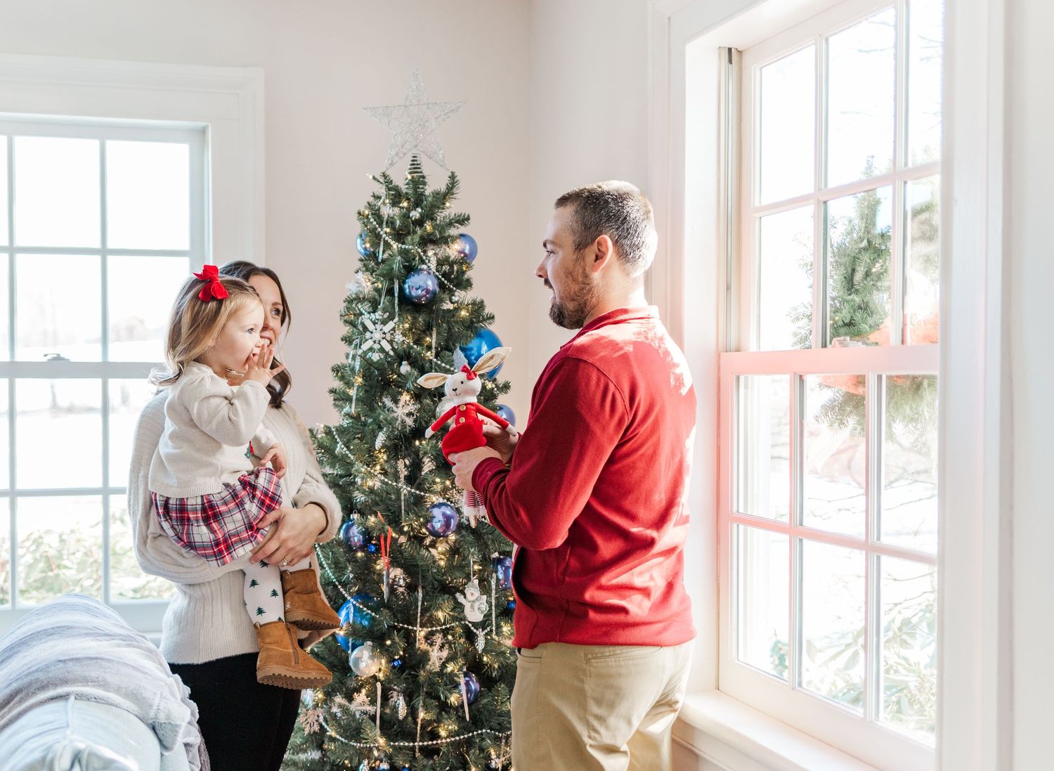 Family laughing by a blue + silver Christmas tree during a light + airy Hudson Valley, NY Christmas Mini Session.