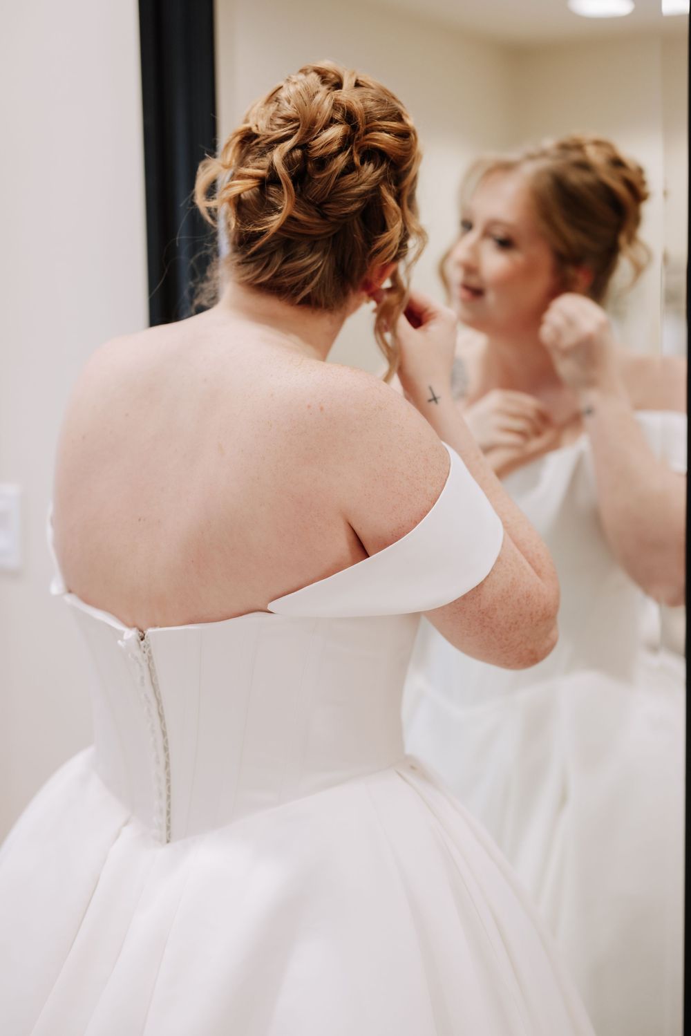 Close-up view of a white wedding dress being buttoned up, showing delicate details along the back closure.