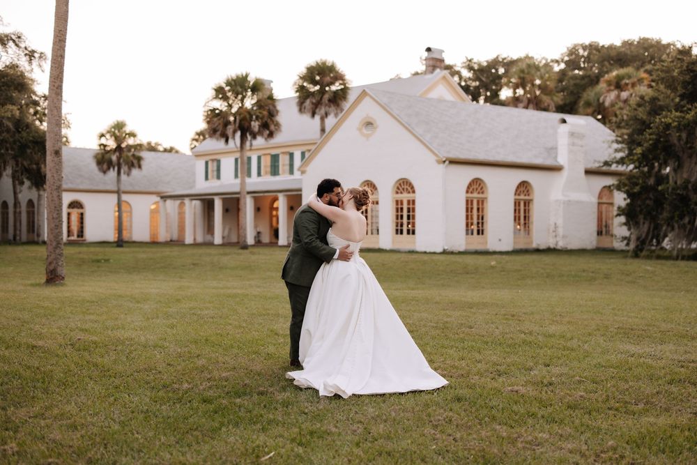 A beautiful white wedding venue with palm trees stands against a sunset sky in Florida.