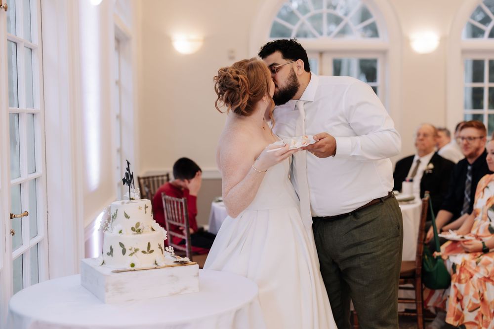 Wedding guests dance and celebrate together in an elegant indoor reception venue with white decor and warm lighting.
