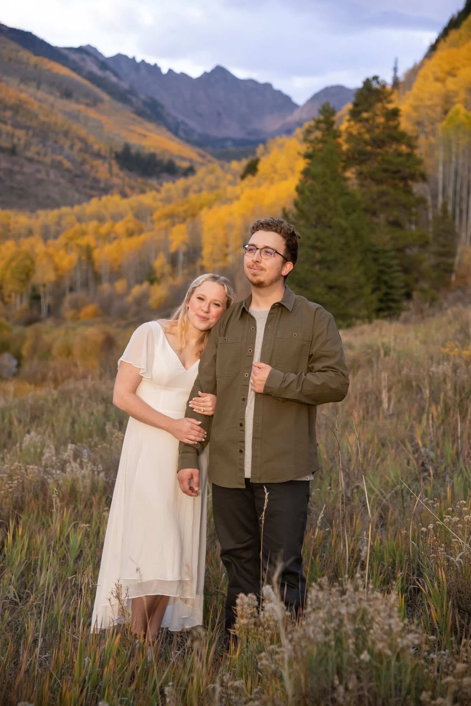 gorgeous engagement photos in Vail Colorado with a cute couple standing in golden fall yellow colors with mountain peaks in the background