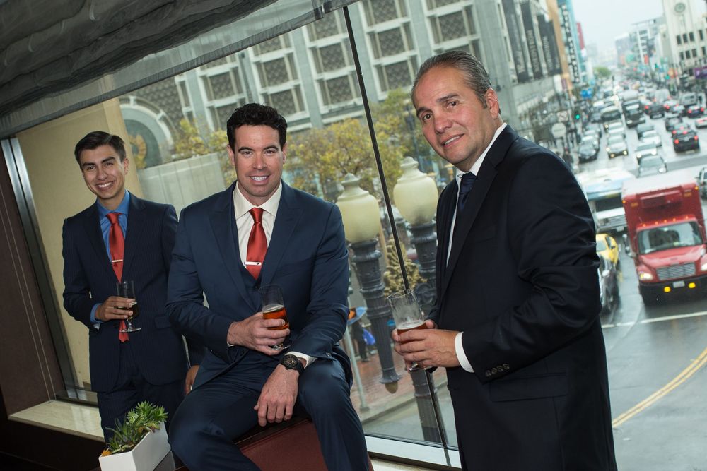 Groomsmen wearing blue suits having a drink in a highrise bar before the wedding.