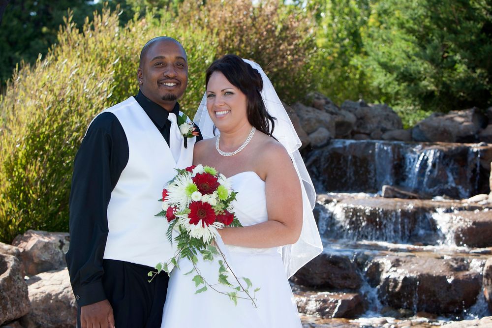 A couple shares romantic moments during their wedding photoshoot by a cascading waterfall in a scenic outdoor setting.