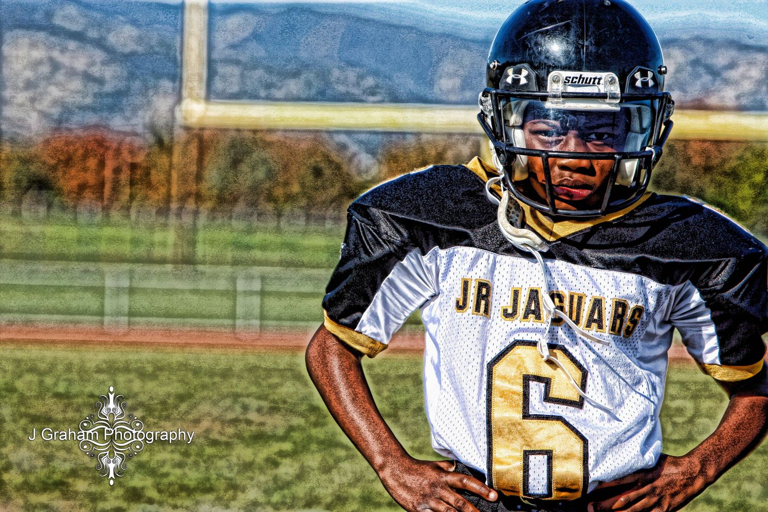 A football player in a black and white jersey with number 6 stands on a field with mountains in the background.
