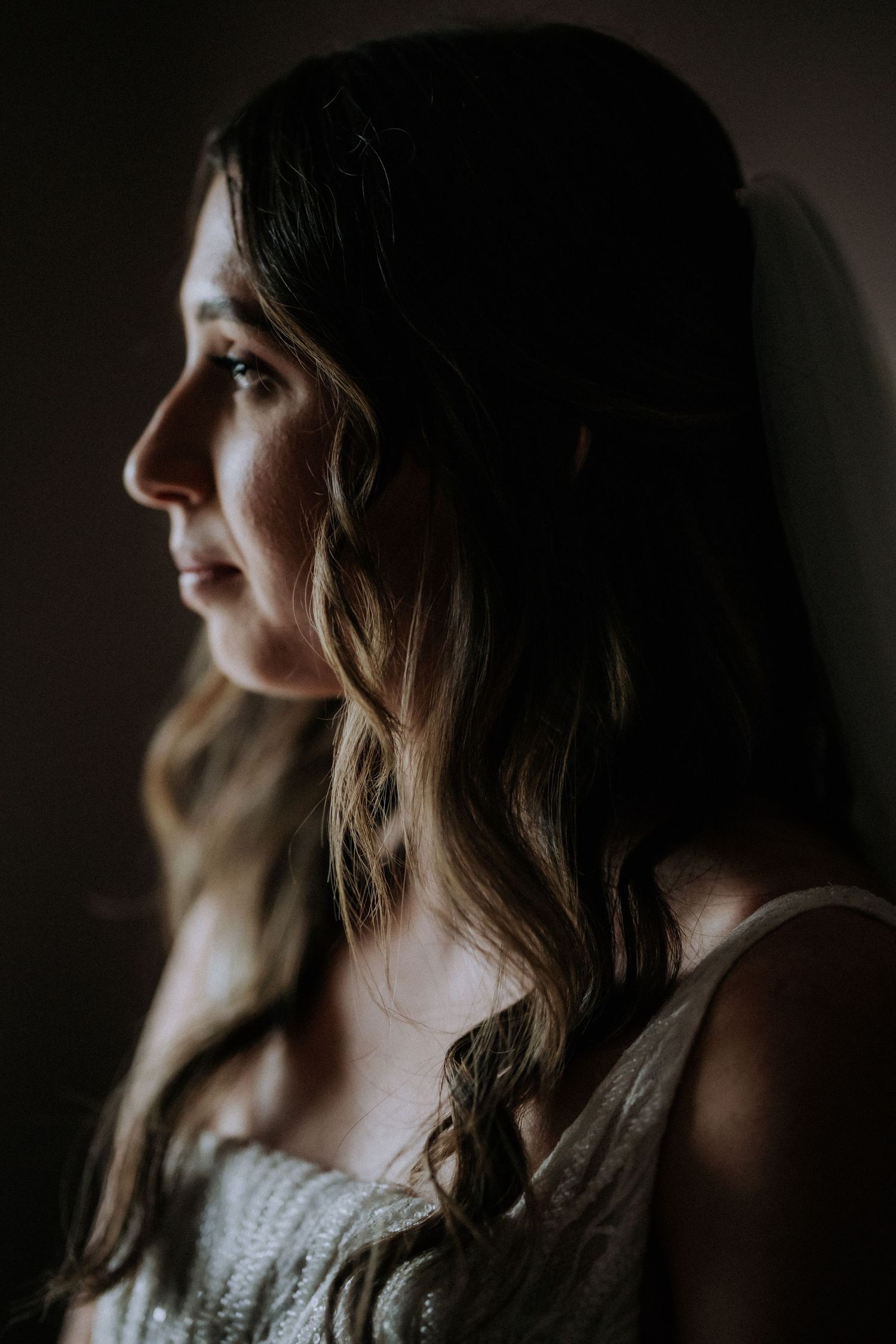 Dramatic side profile portrait in moody lighting with soft focus.