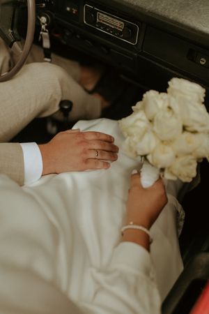 Detail shot of white fabric and hands arranging wedding dress material.