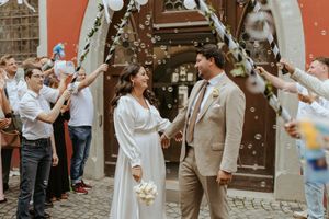 Wedding celebration outside a brick building with guests throwing confetti in celebration.