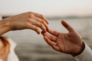 Close-up of hands reaching towards each other against a blurred background.
