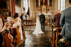 Wedding ceremony taking place in ornate traditional church interior.