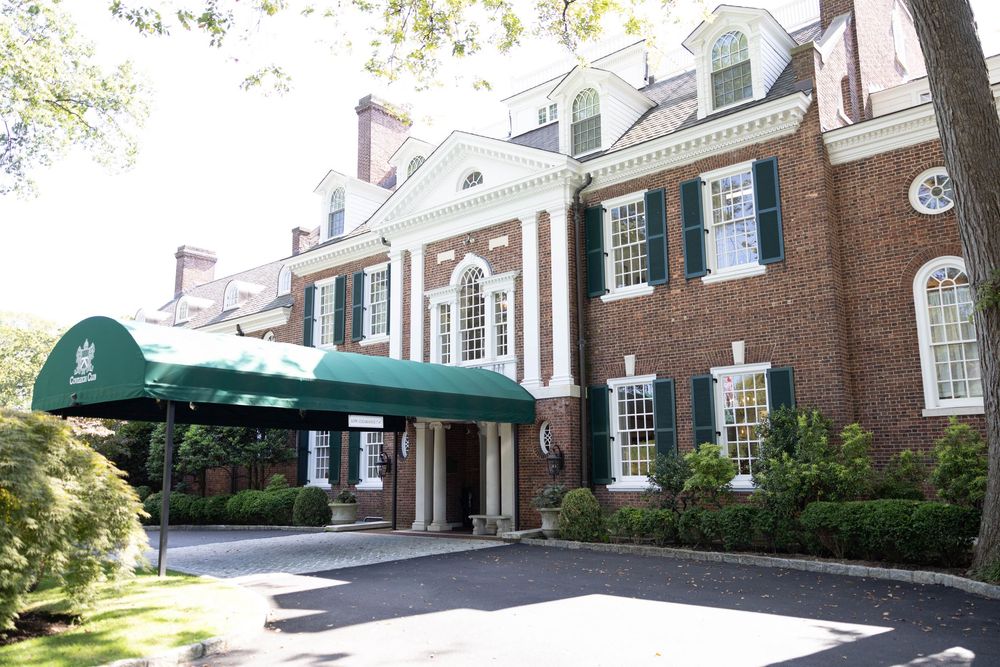 Exterior view of traditional brick colonial houses with white trim and columns in an upscale residential neighborhood.