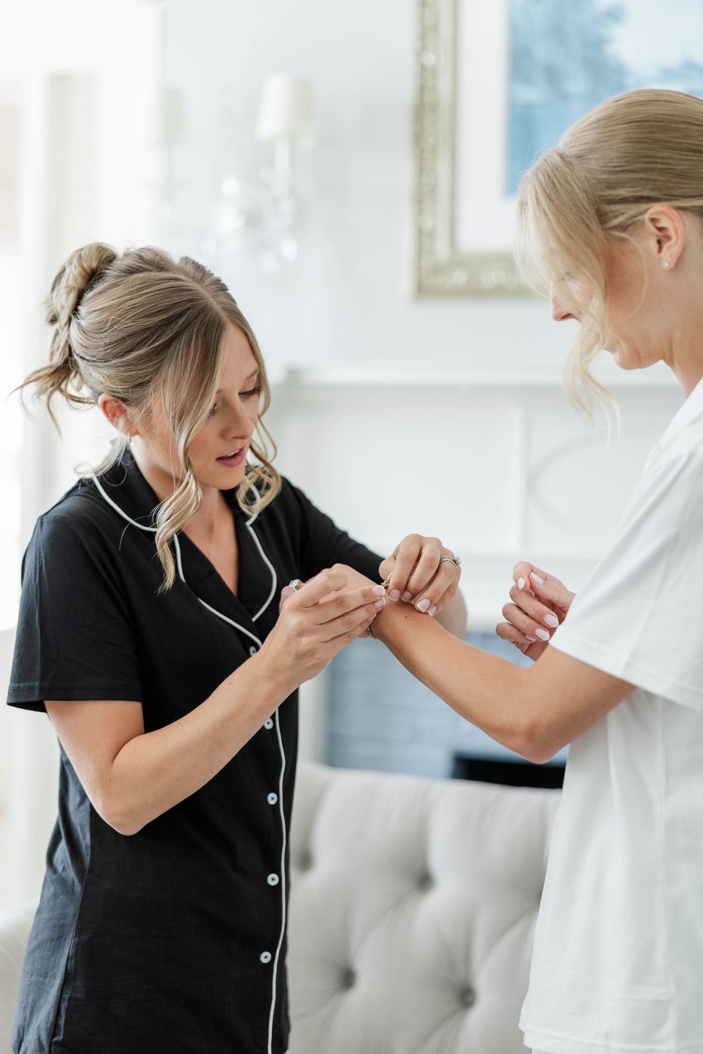 Two people in contrasting black and white outfits share a joyful moment while getting ready.