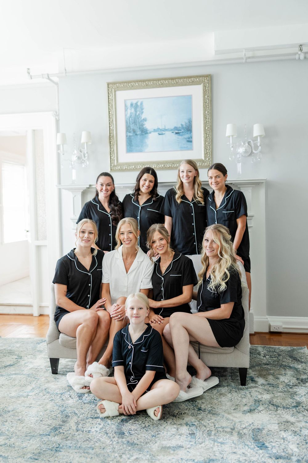 A group photo in a bright room with matching black sleepwear gathered around an elegant white fireplace.