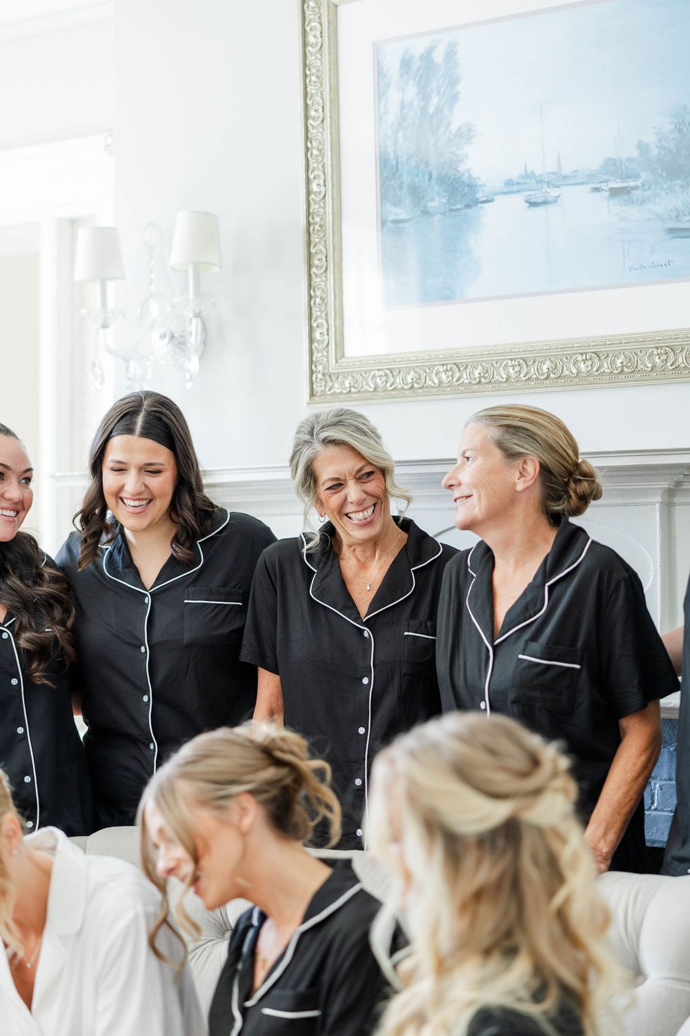 A group wearing matching black and white pajama-style outfits share laughter and smiles in a bright room with artwork.