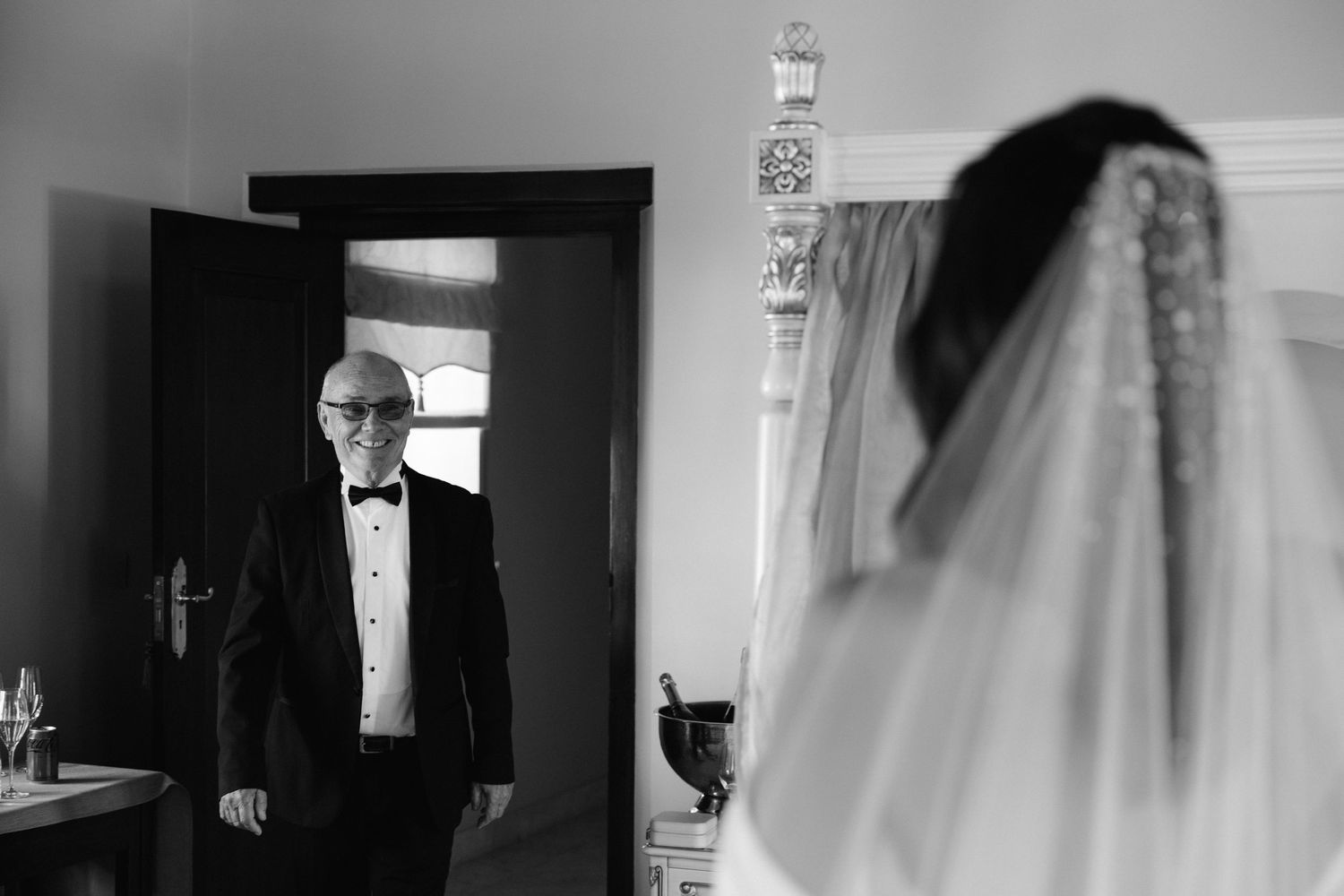 Black and white wedding photo showing a bride in her veil and dress being photographed in a classic moment.