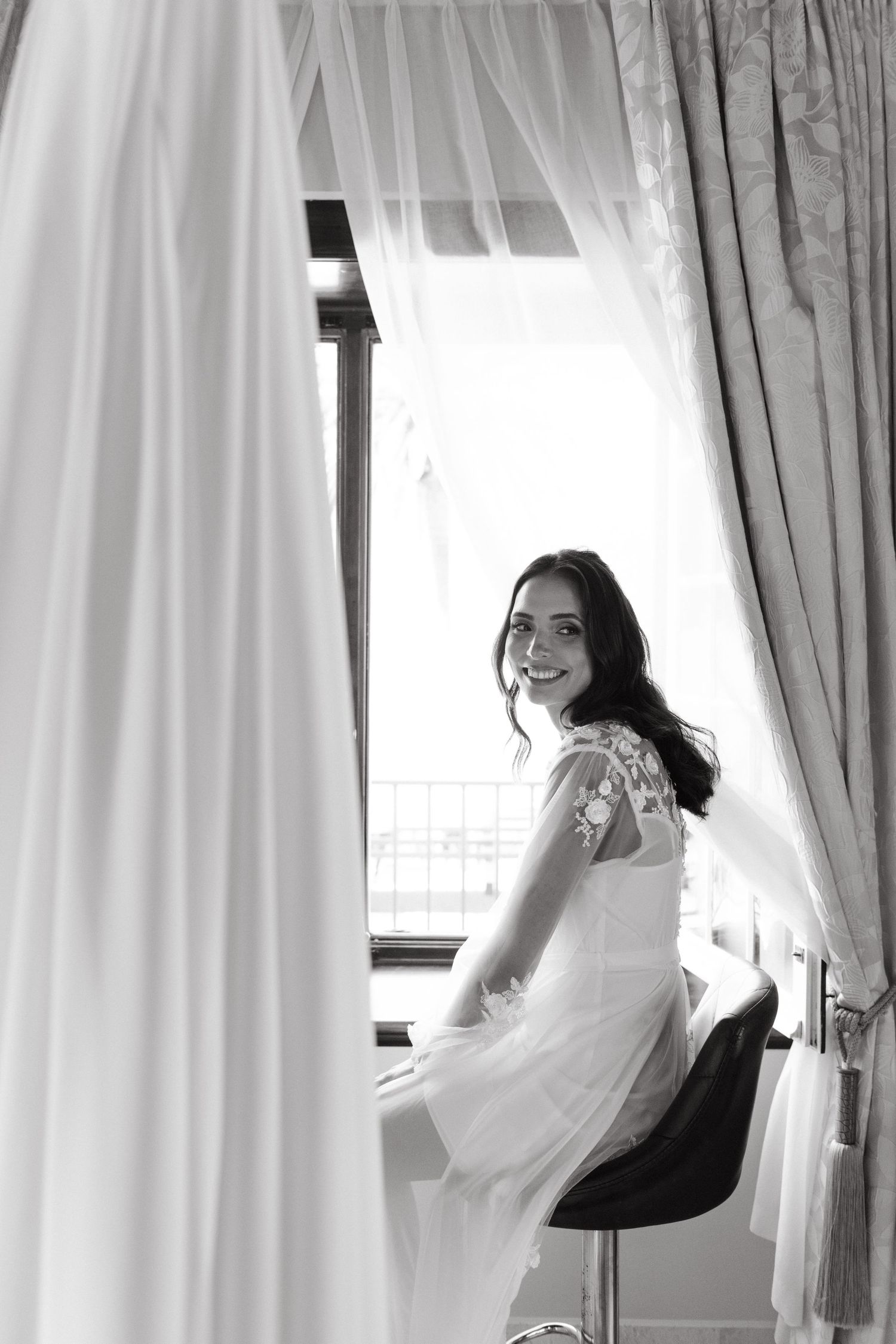 Black and white photo series showing a person peeking through white curtains in different poses.