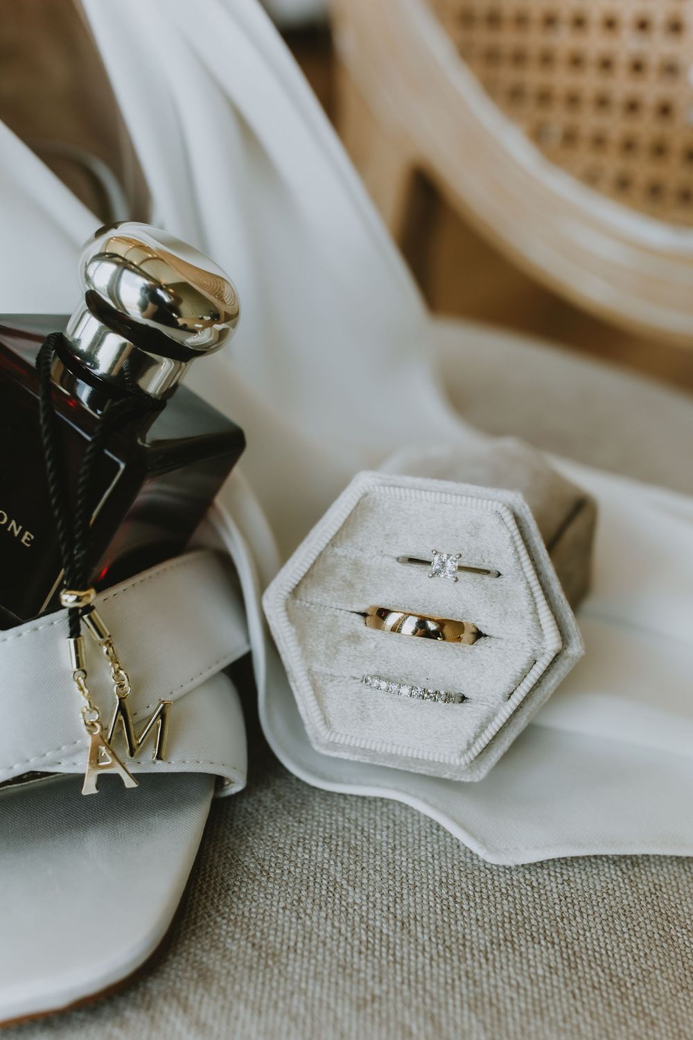 Close-up sequence of wedding rings displayed on a hexagonal white ring holder against a textured gray fabric background.